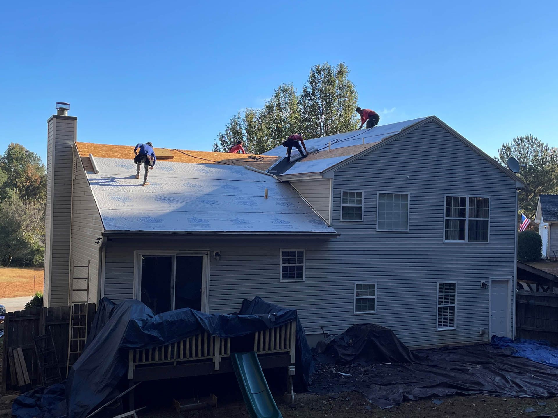 A group of people are working on the roof of a house.