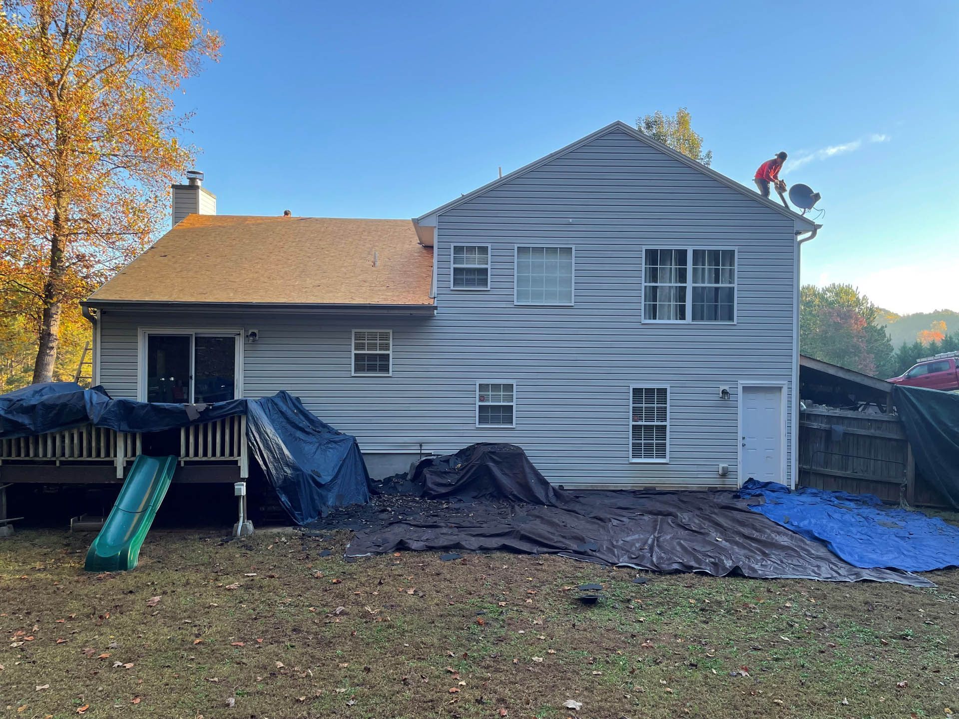 A man is standing on the roof of a house.
