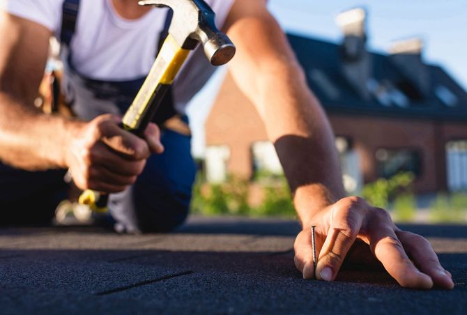 a man is using a hammer to fix a roof.