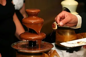 a person is pouring chocolate into a chocolate fountain .