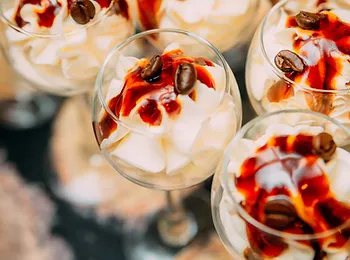 a close up of a dessert in a glass with whipped cream and coffee beans .