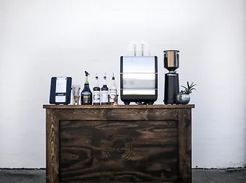 a wooden bar filled with bottles , glasses , and a coffee machine .
