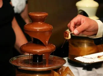 a person is dipping a marshmallow into a chocolate fountain .