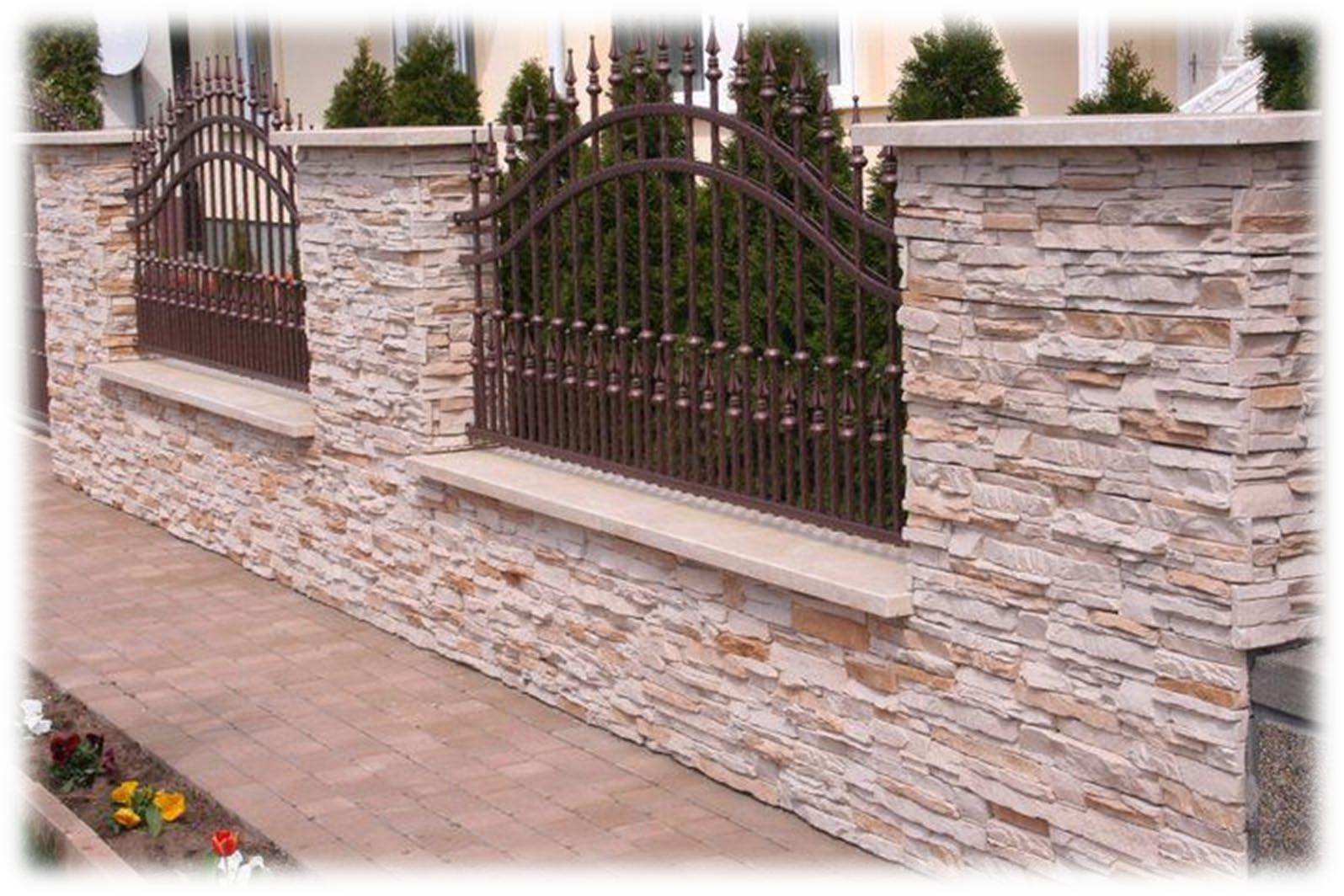 Un muro di pietra con una recinzione in ferro battuto davanti a una casa.