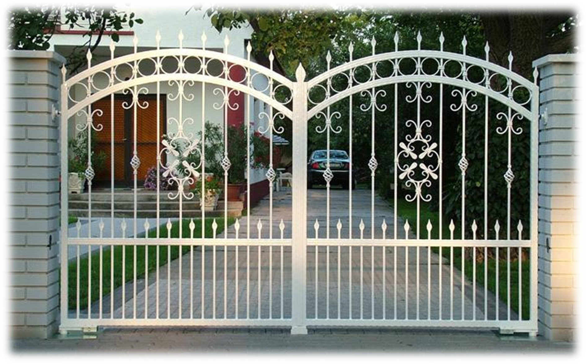 Un cancello bianco in ferro battuto è aperto su un vialetto