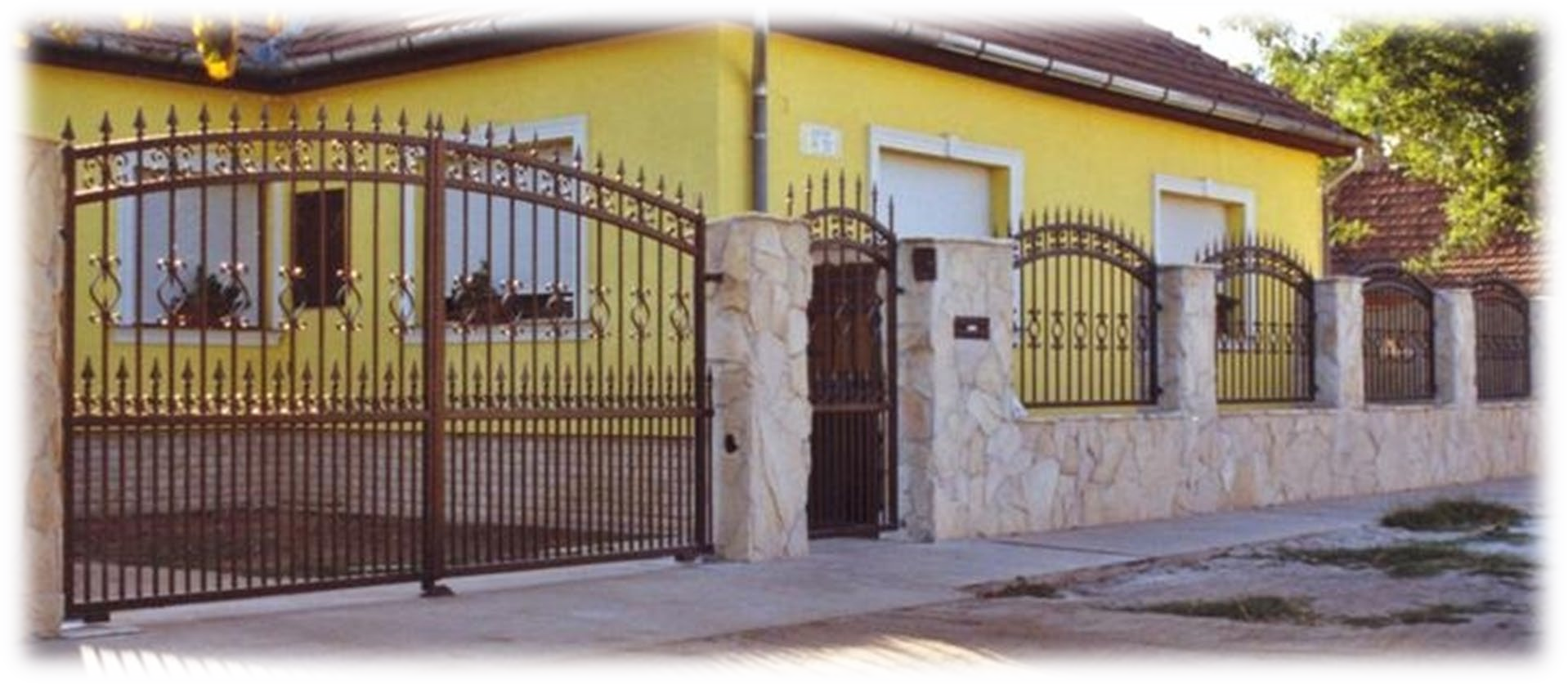 Una casa gialla con un cancello in ferro battuto davanti