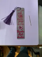 A bookmark with a purple tassel is sitting on top of a piece of paper.