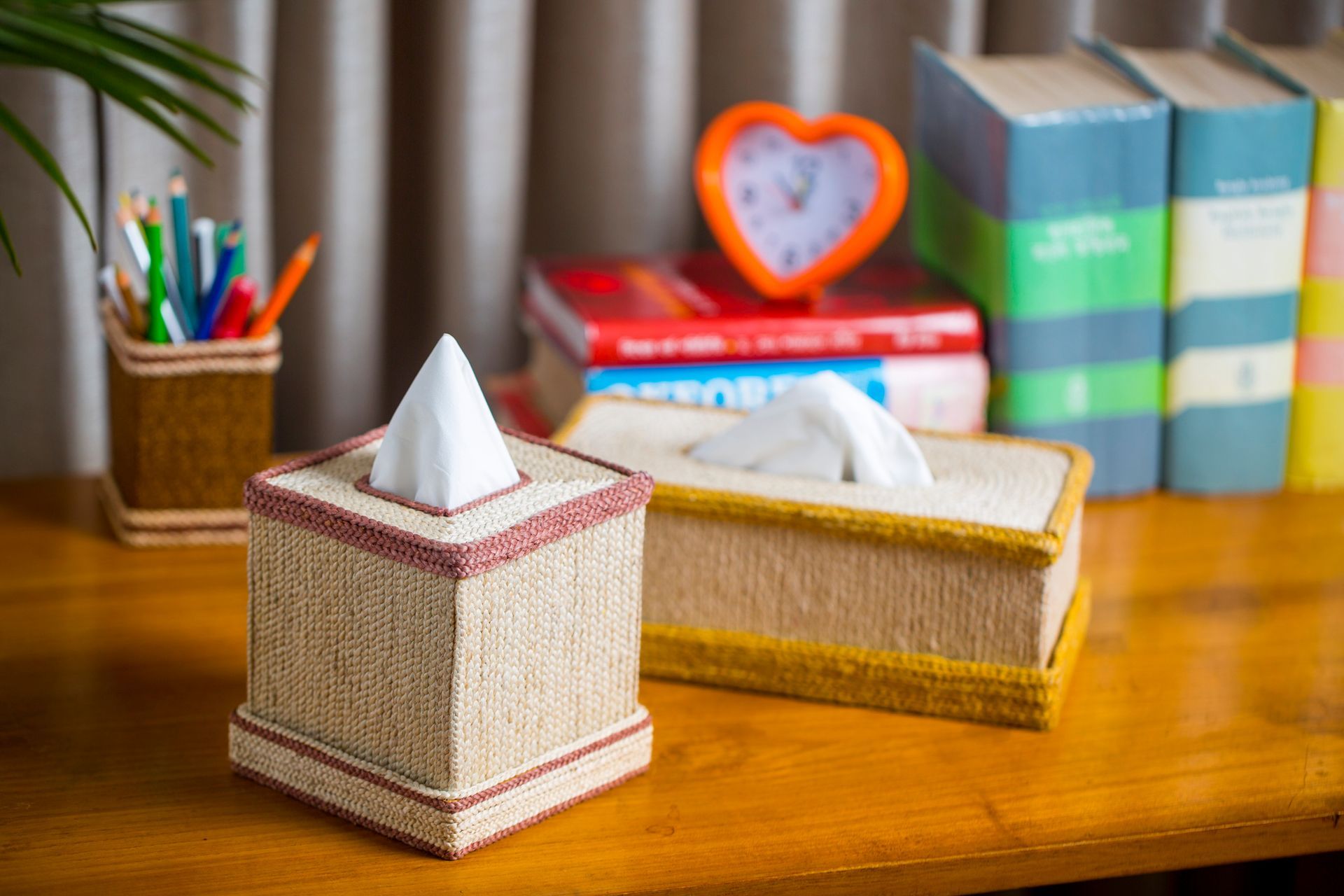 Two tissue boxes are sitting on a wooden table.