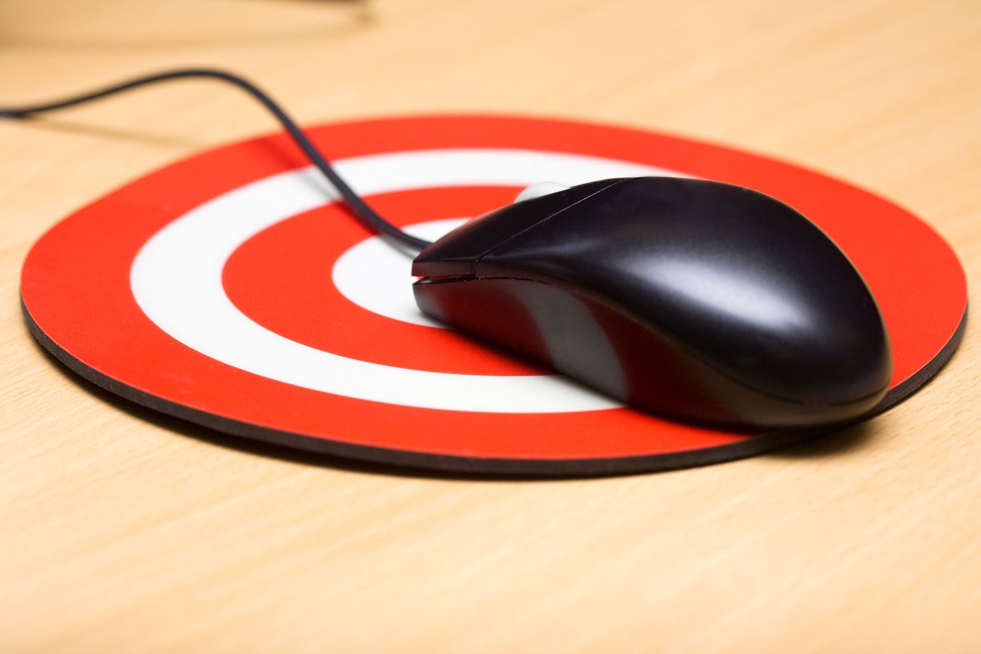 A computer mouse is sitting on a red and white target mouse pad