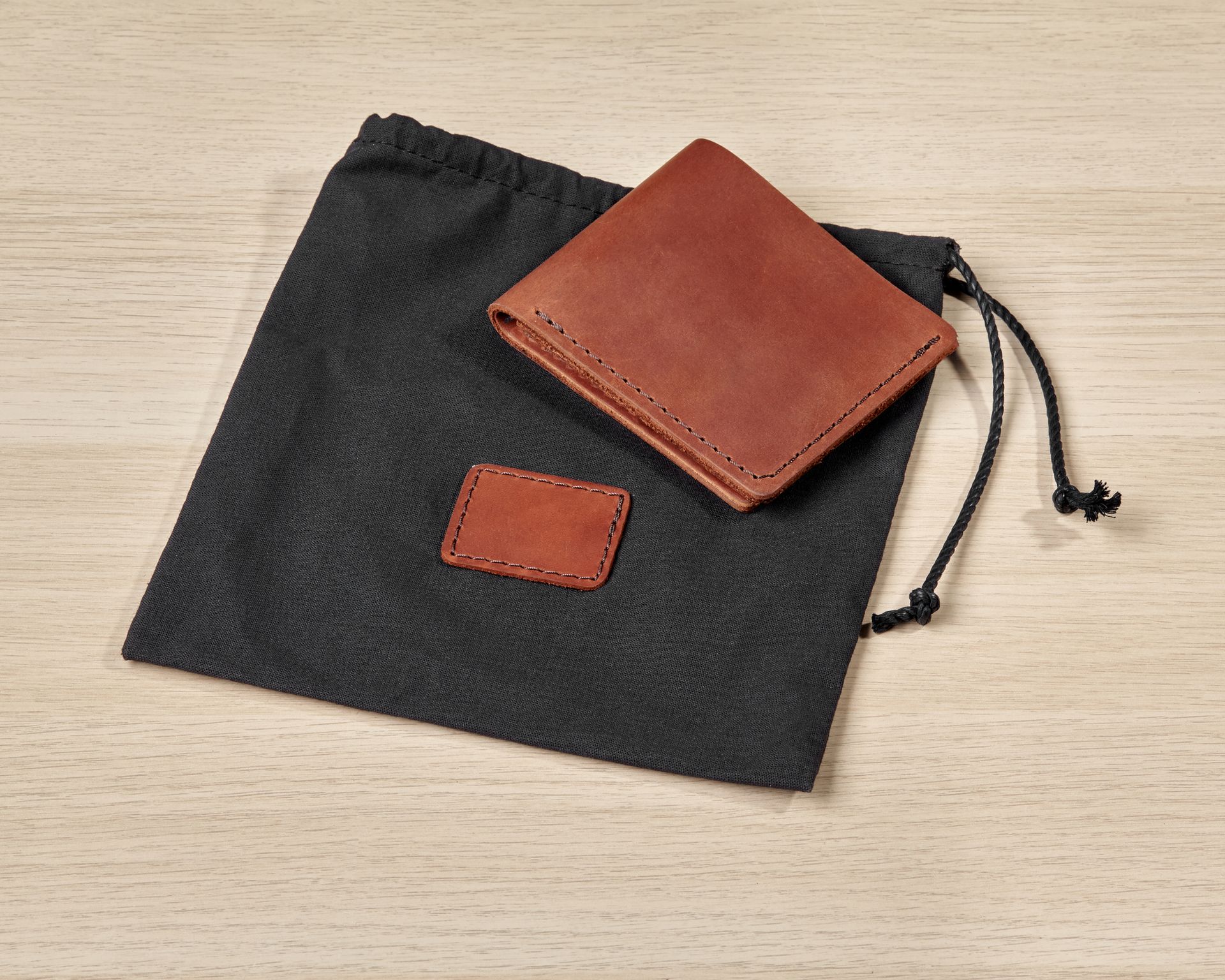 A brown leather wallet is in a black bag on a wooden table.