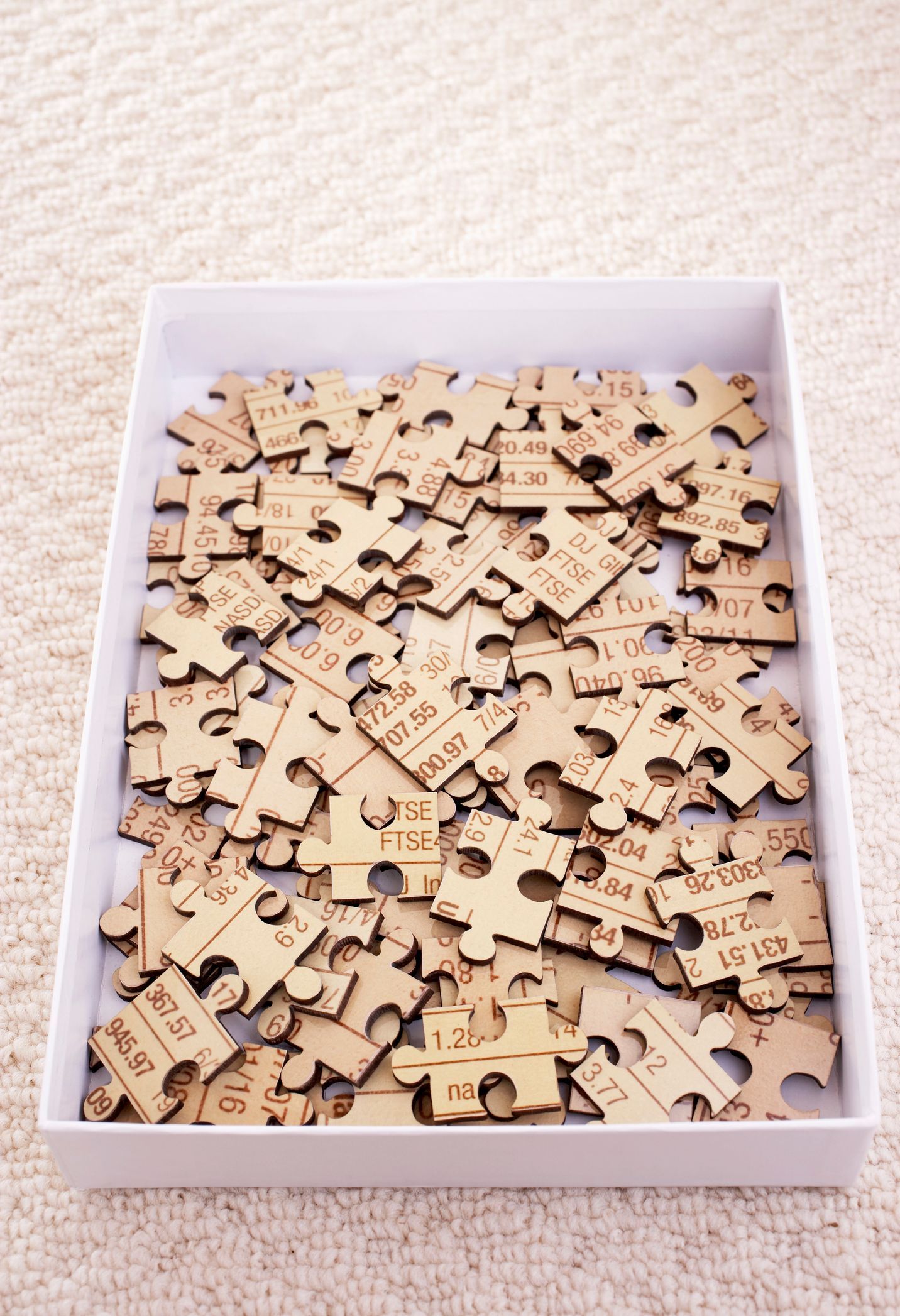 A pile of wooden puzzle pieces in a white box