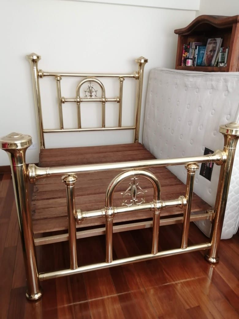Estructura de cama de latón con base de láminas de madera, para interior. cabecero y el pie de cama presentan arcos decorativos.