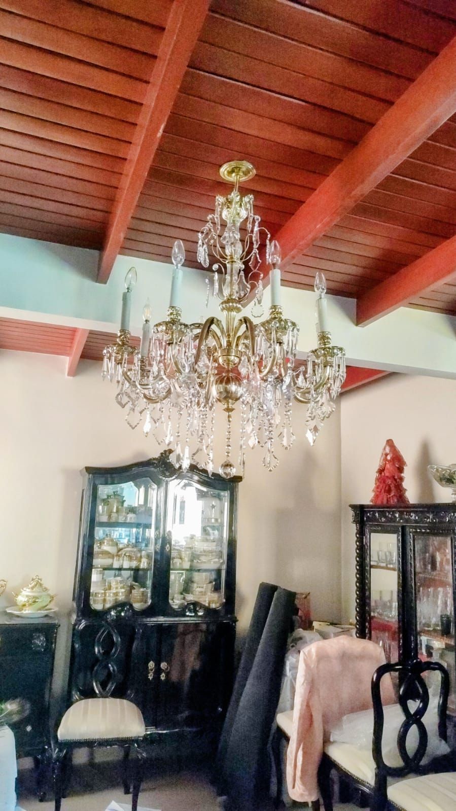 Lámpara de araña blanca con hilos de cristal, suspendida de una lámpara de techo de metal, en el interior.