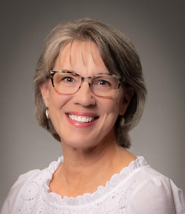 A woman wearing glasses is smiling for the camera.