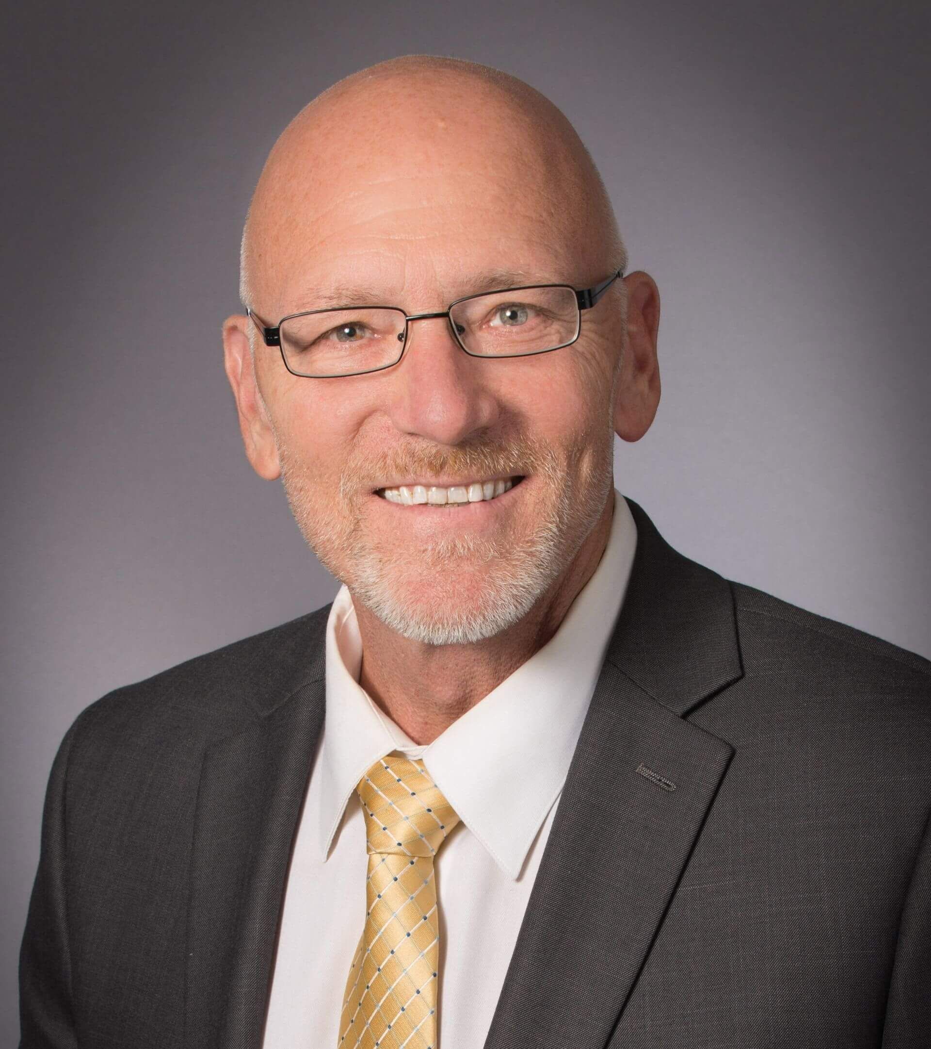 A man in a suit and tie is smiling for the camera