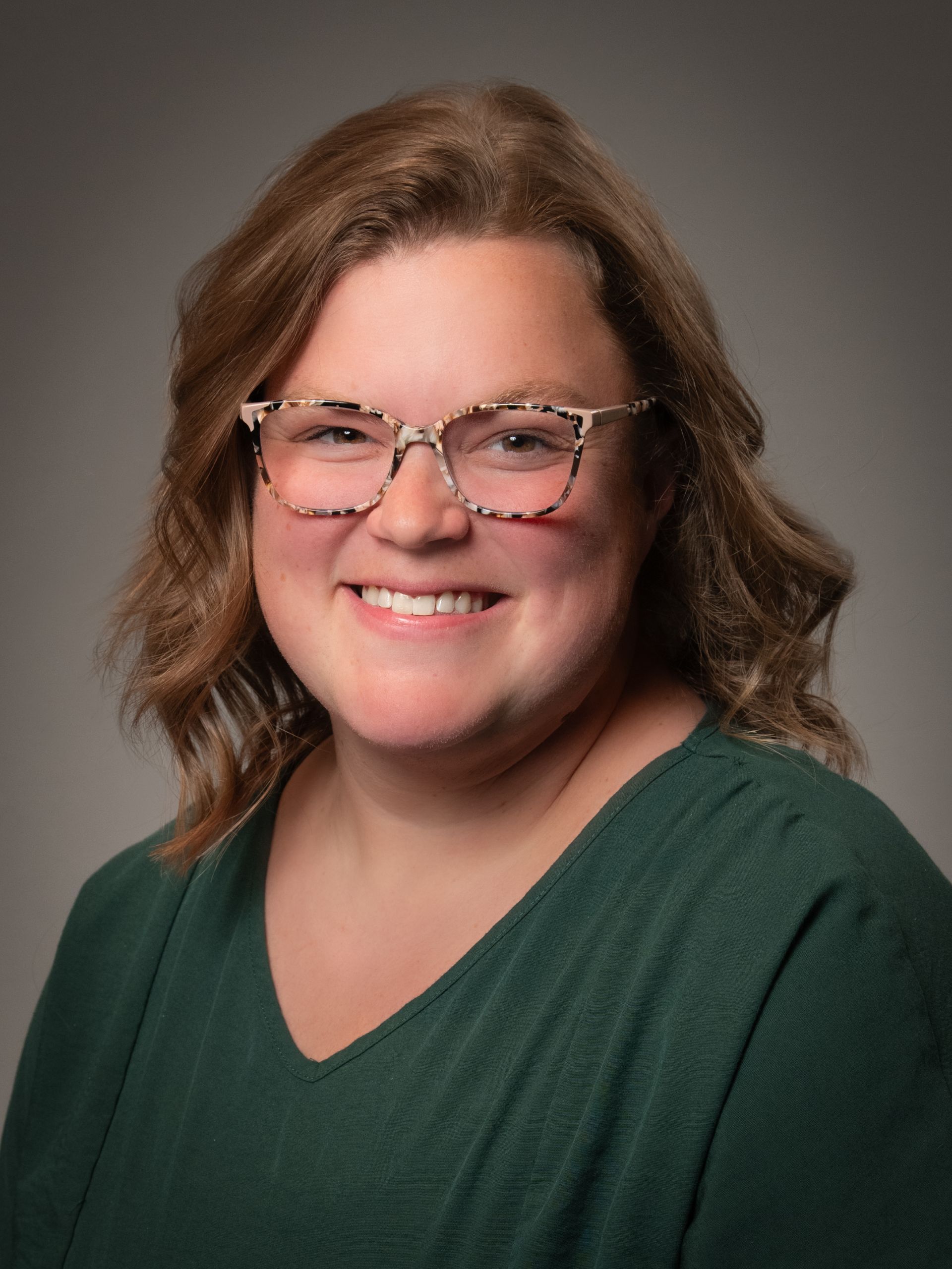 A woman wearing glasses is smiling for the camera.