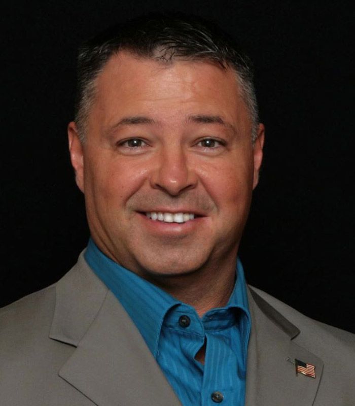 A man in a suit and blue shirt smiles for the camera