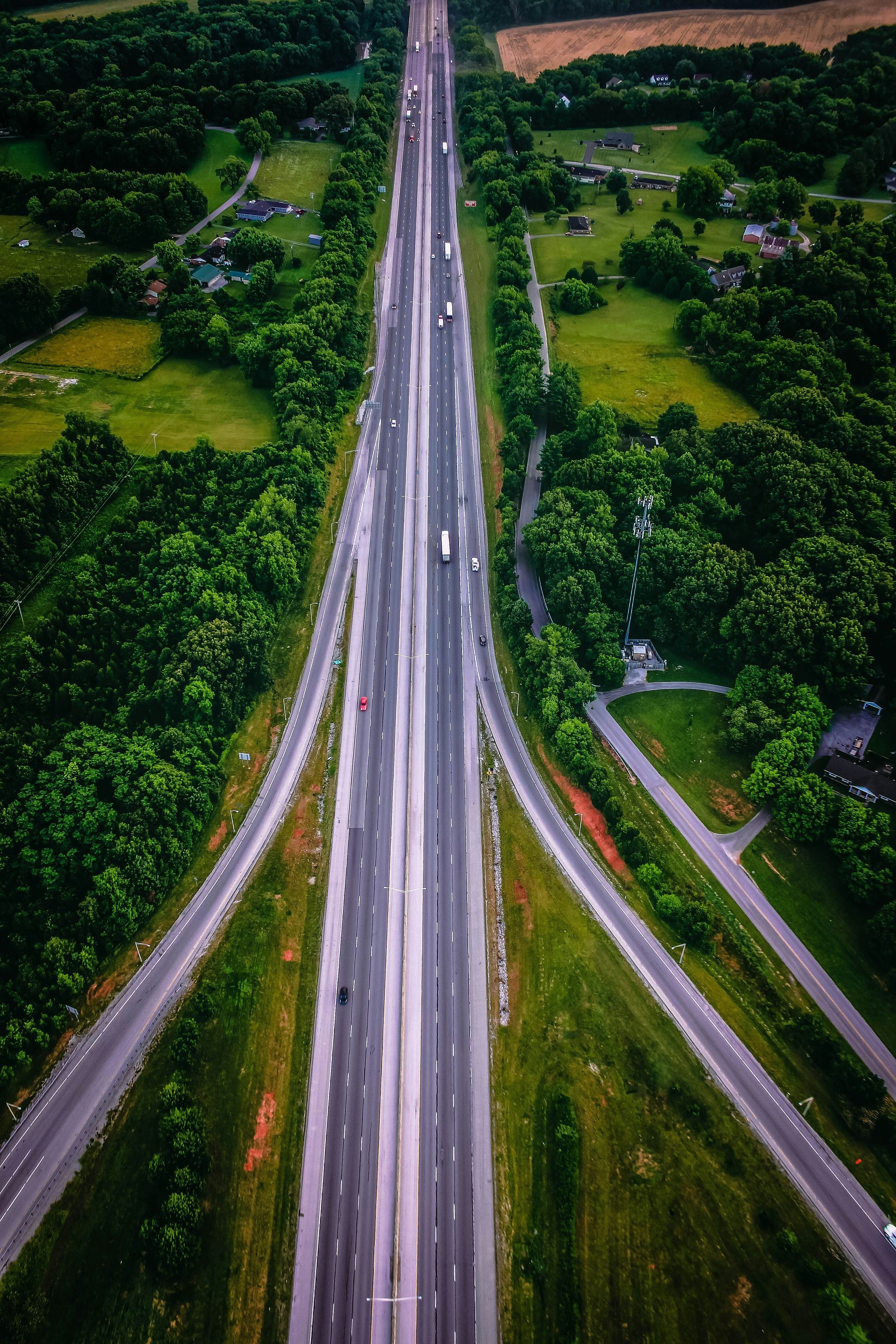 An aerial view of a highway surrounded by trees and grass.