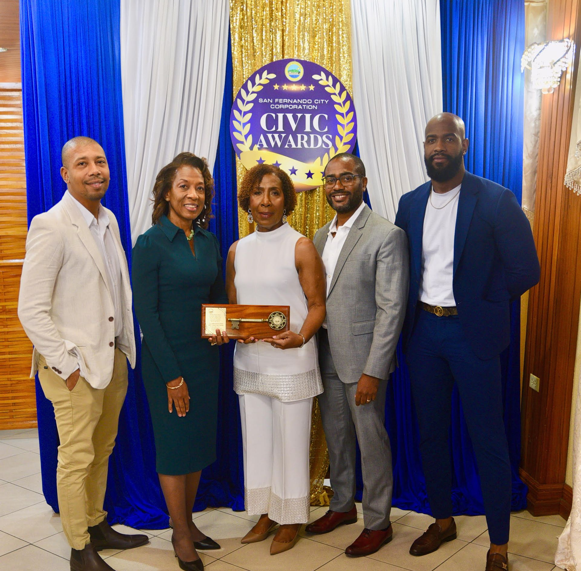Five people posing with a civic award plaque in front of a Civic Awards backdrop.