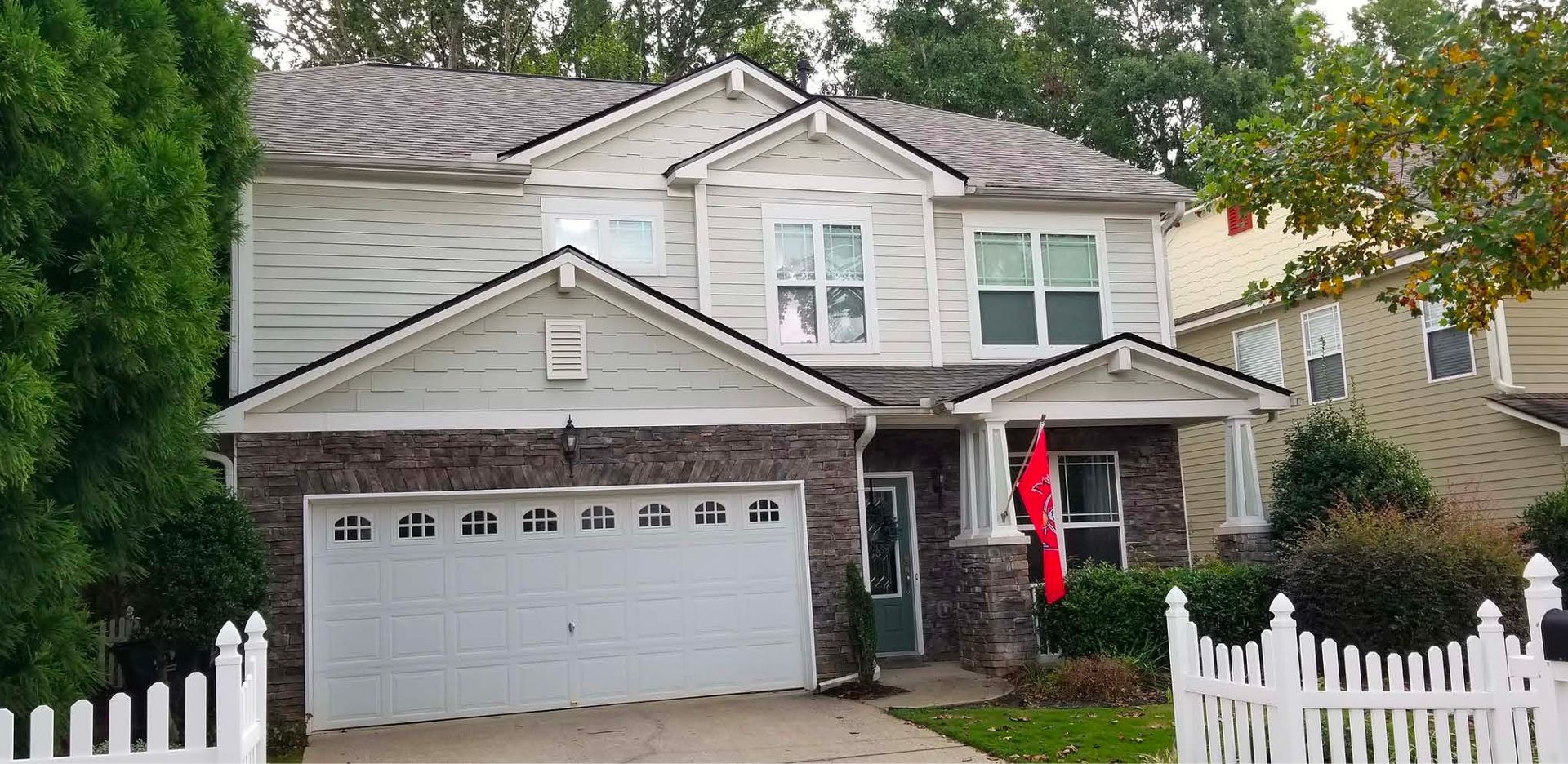 A large house with a white fence and a red flag in front of it.