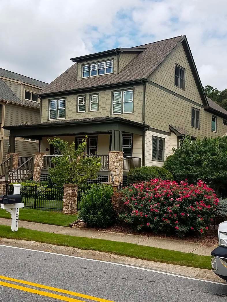 A large house with solar panels on the roof is sitting next to a street.