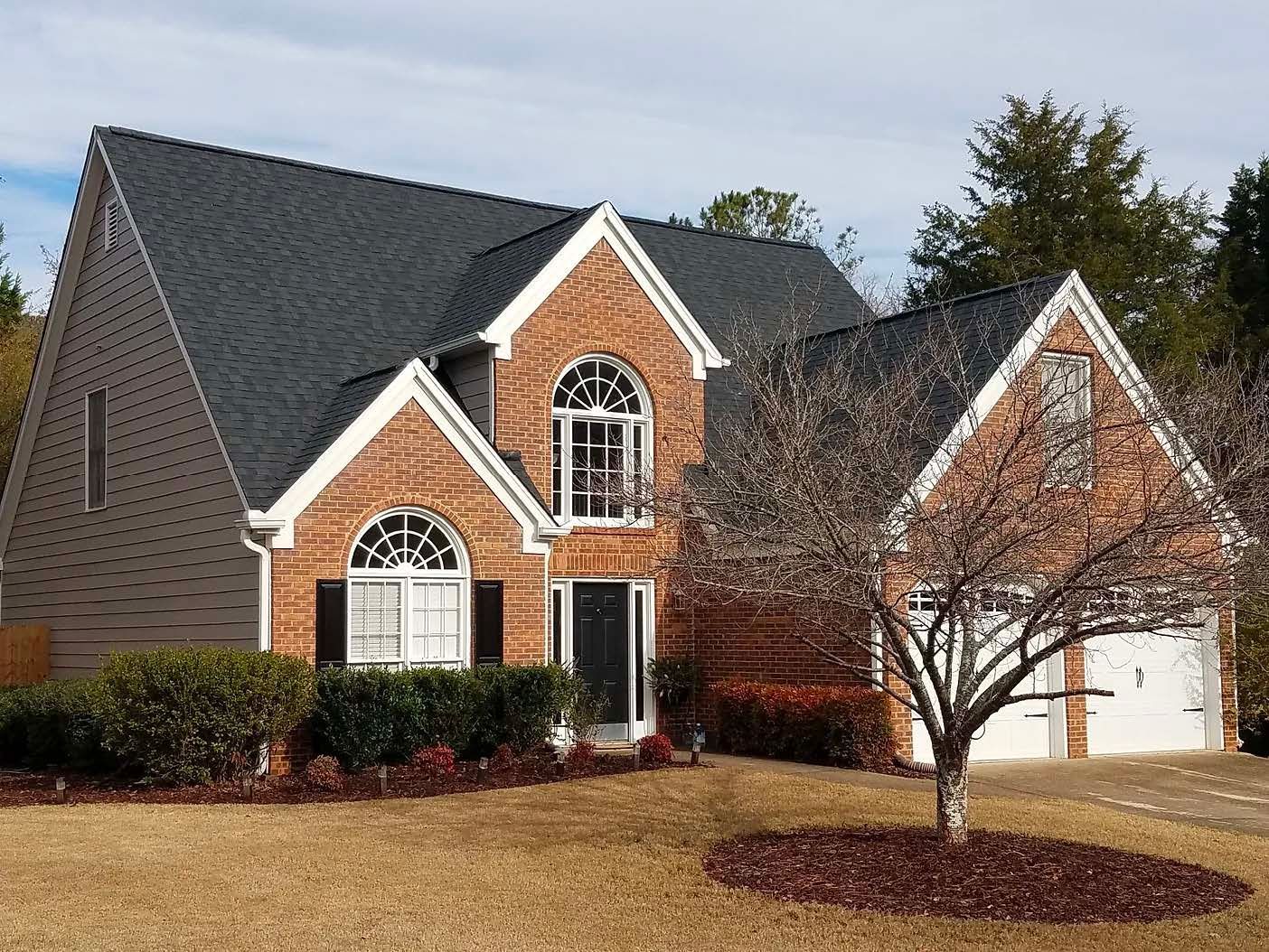 A large brick house with a tree in front of it