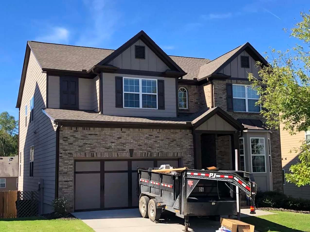 A dumpster is parked in front of a large house.