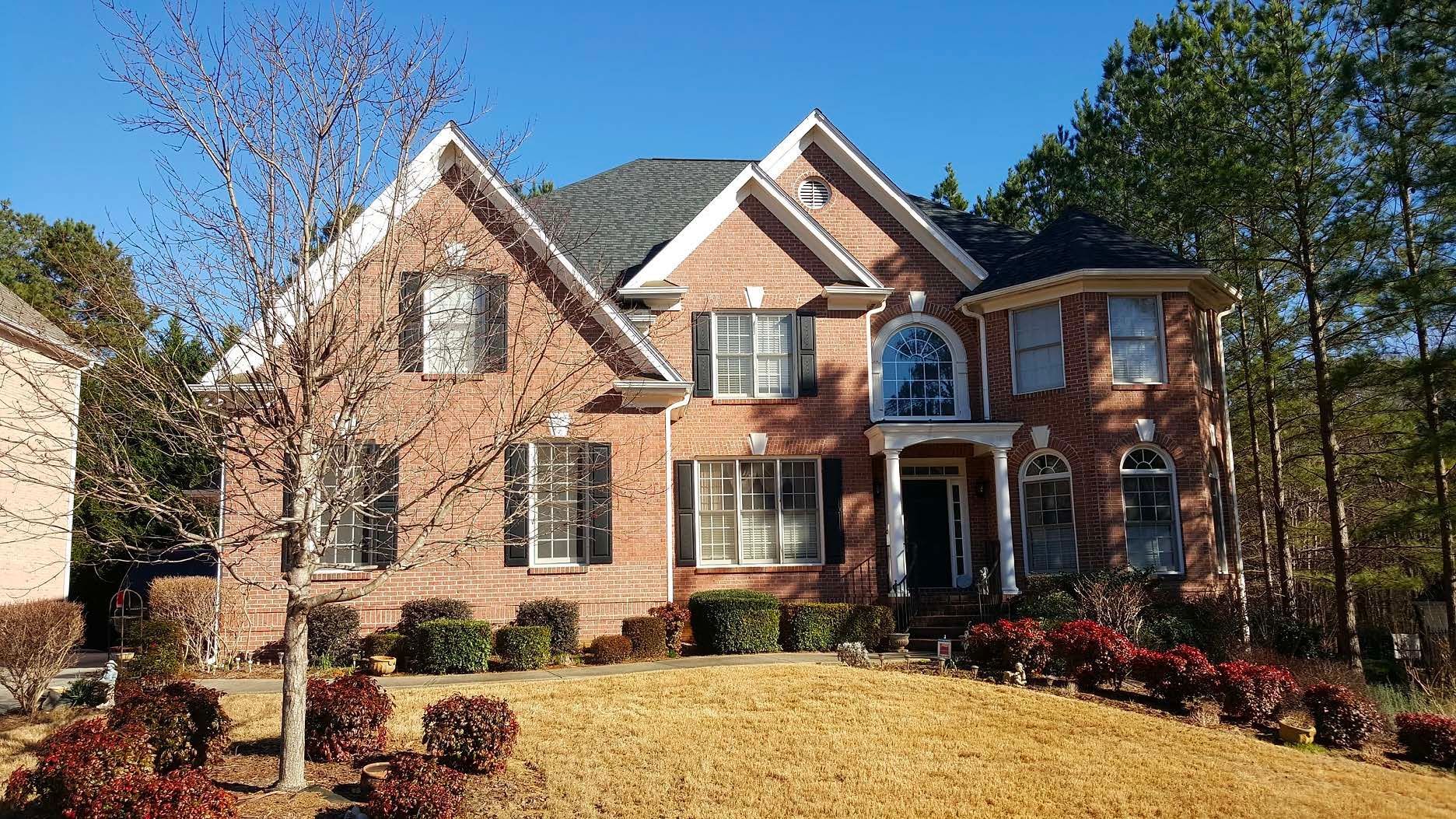 A large brick house with a lush green lawn in front of it