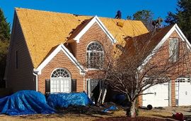 A large brick house with a roof that is being repaired