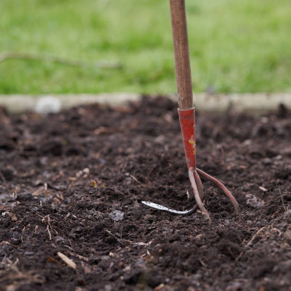 A Rake Is Sitting In The Dirt In A Garden — Southern Turf Supplies In Batemans Bay, NSW