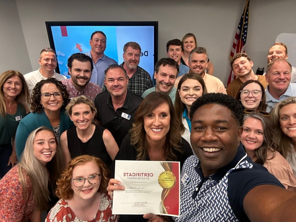 A group of people are posing for a selfie while holding a certificate.