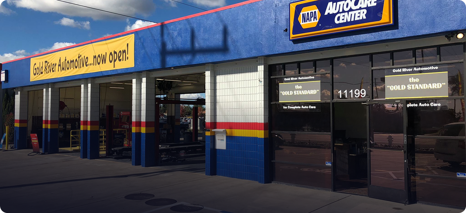 A NAPA AutoCare Center building with blue, white, and red exterior walls under a bright blue sky - Gold River Automotive