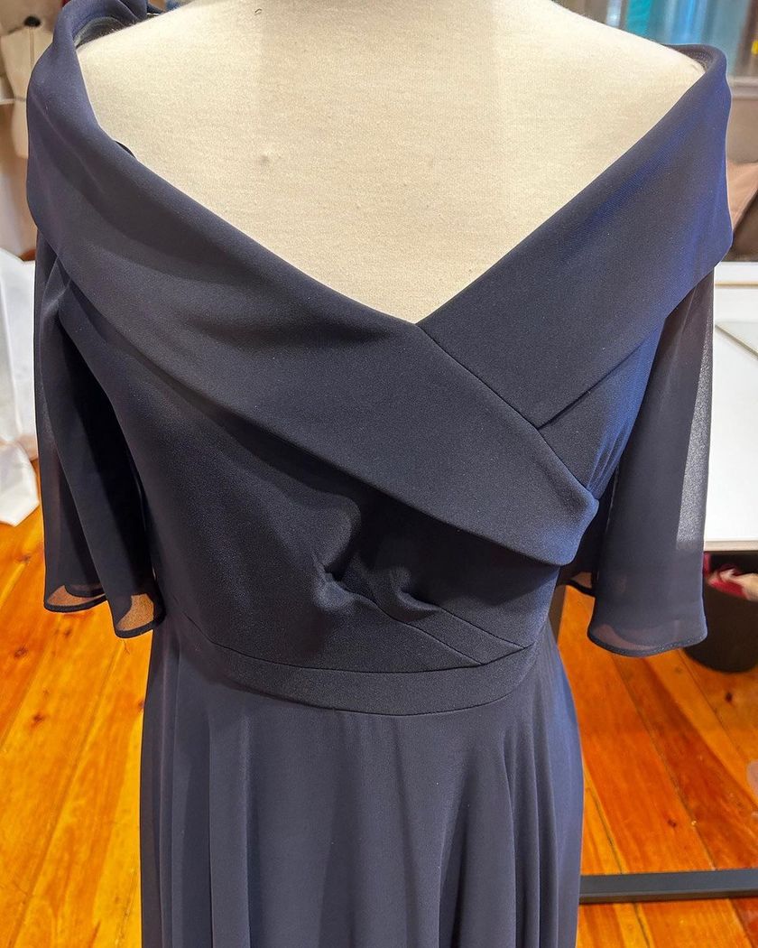 Navy off-the-shoulder dress with draped neckline on a mannequin