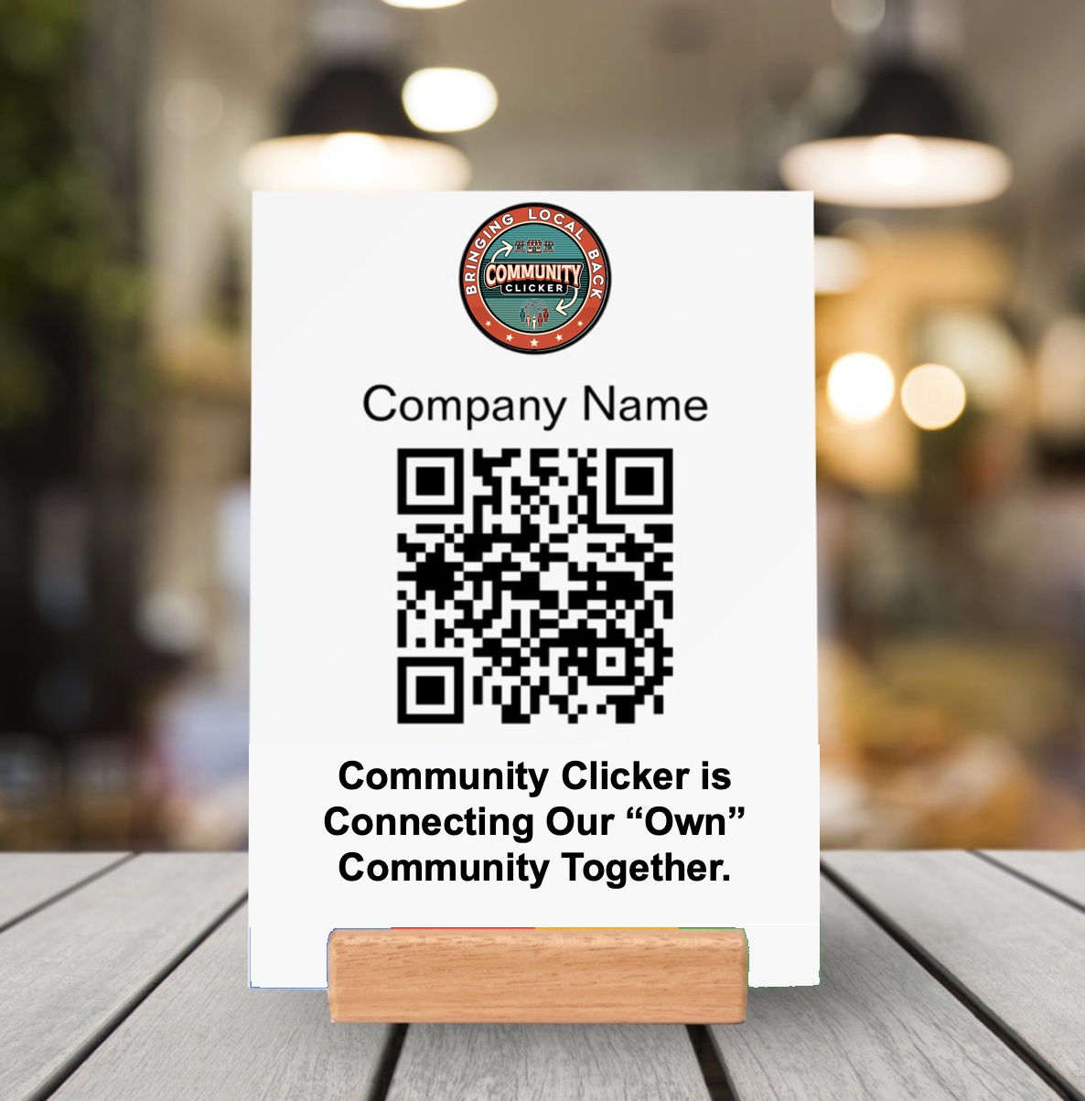 White sign with QR code, logo, and text on a wooden stand in a cafe setting.