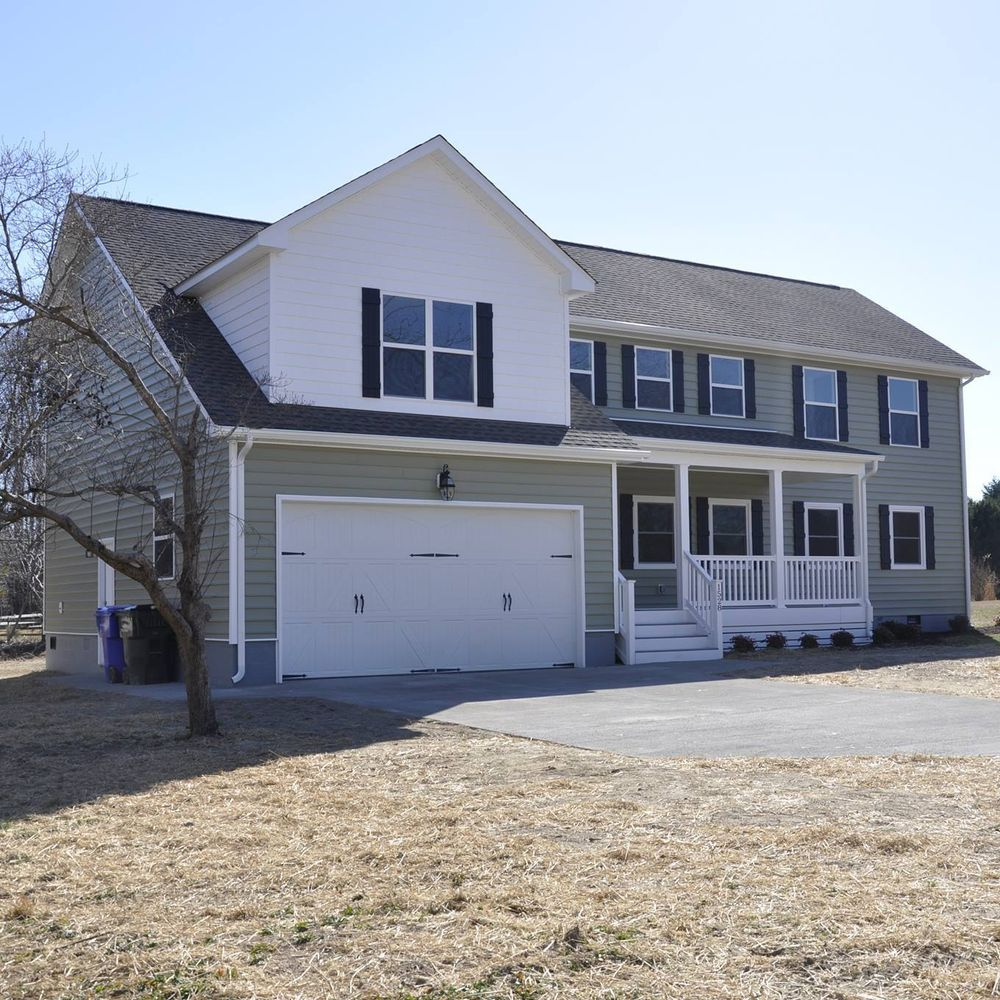 Two-story house with green siding, white trim, attached garage, and a front porch.