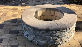 Stone fire pit with a surrounding circular paved patio.