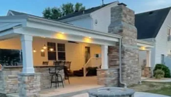 Outdoor patio with stone accents, bar, fireplace, and overhead lighting.