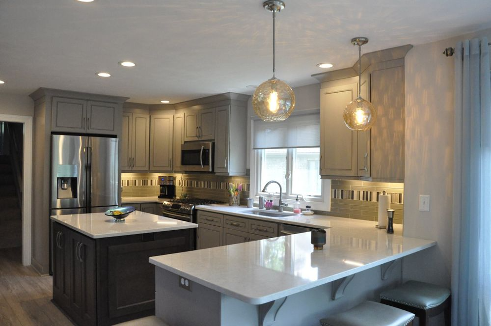 Modern kitchen with gray cabinets, white countertops, and two pendant lights.