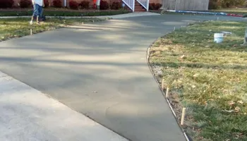 Freshly poured concrete driveway curving into the distance. A person stands nearby.
