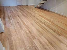 Hardwood floor with natural wood grain, with stairs in background.
