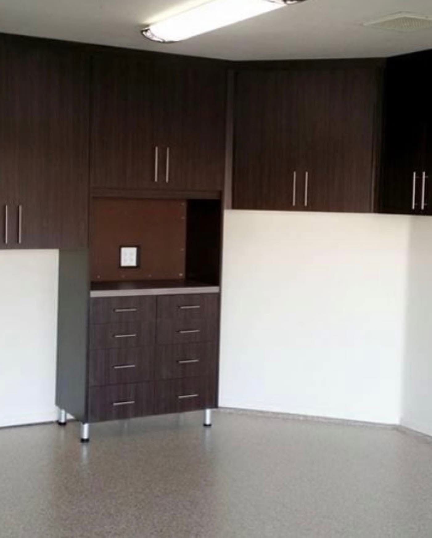 Empty room with dark wood cabinets, white walls, and a light gray floor.
