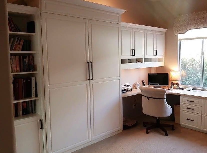 White home office with built-in cabinets, desk, chair, and window light