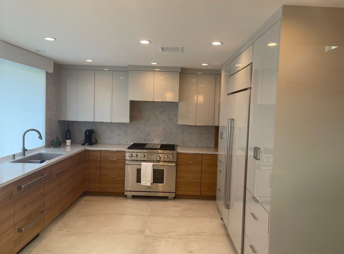 Modern kitchen with white and wood cabinets, stainless steel appliances, and beige tile flooring
