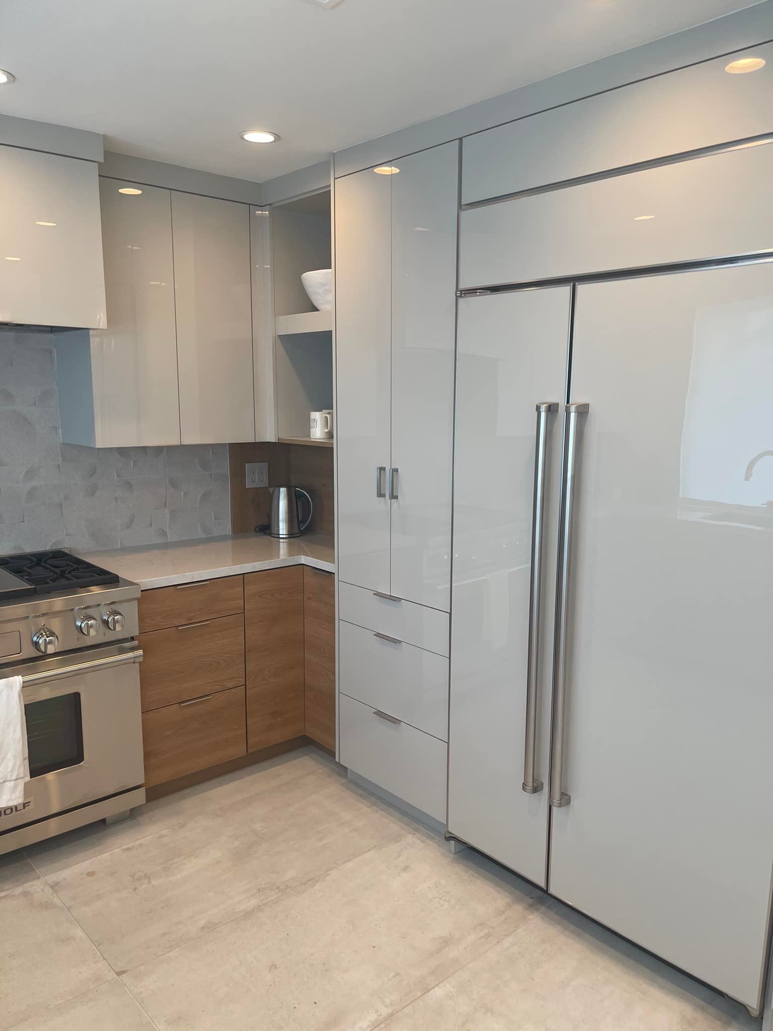 Modern kitchen with white cabinets, stainless appliances, wood drawers, and beige tile floor