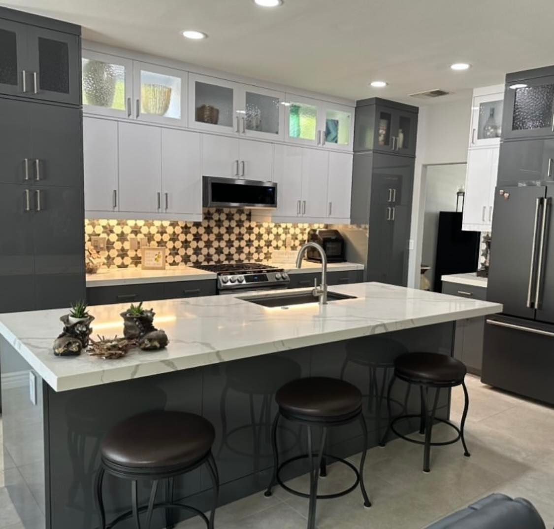Modern gray kitchen with a white island, black stools, and patterned backsplash