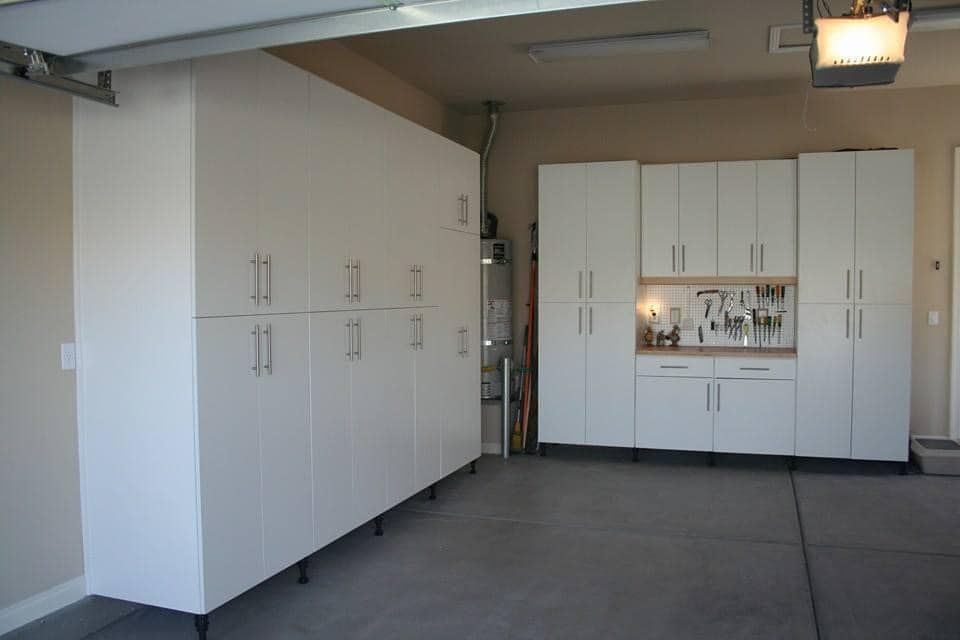 White garage cabinets and workbench along a concrete floor in a clean storage space