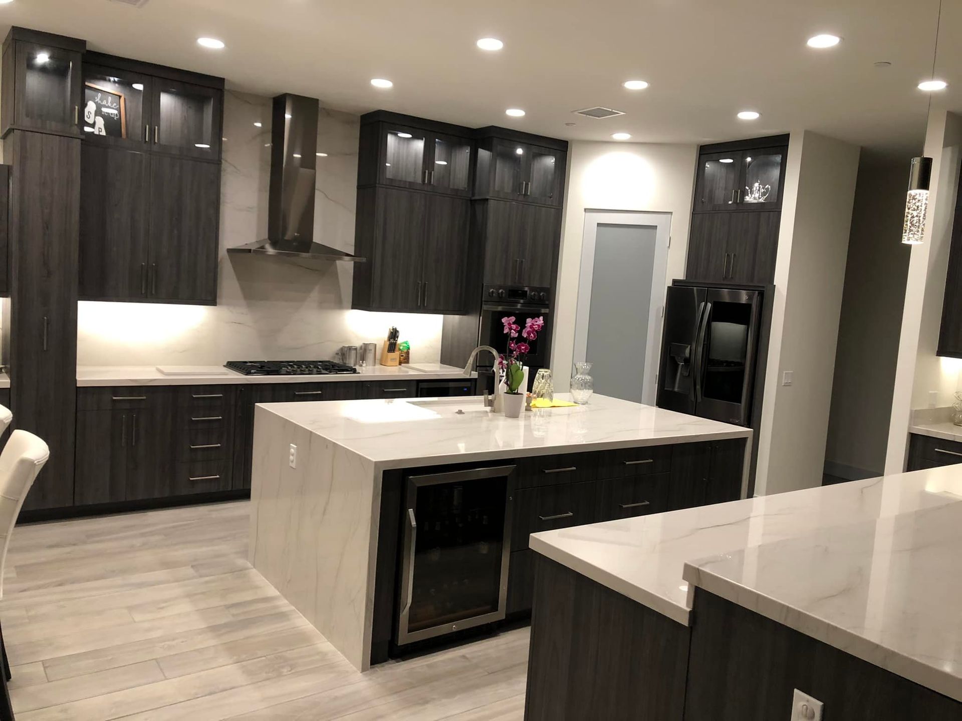 Modern kitchen with dark cabinets, white island, and recessed lighting