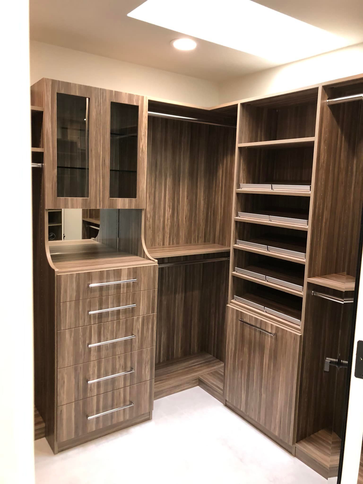 Wood-paneled walk-in closet with shelves, drawers, hanging space, and shoe racks under bright ceiling lights