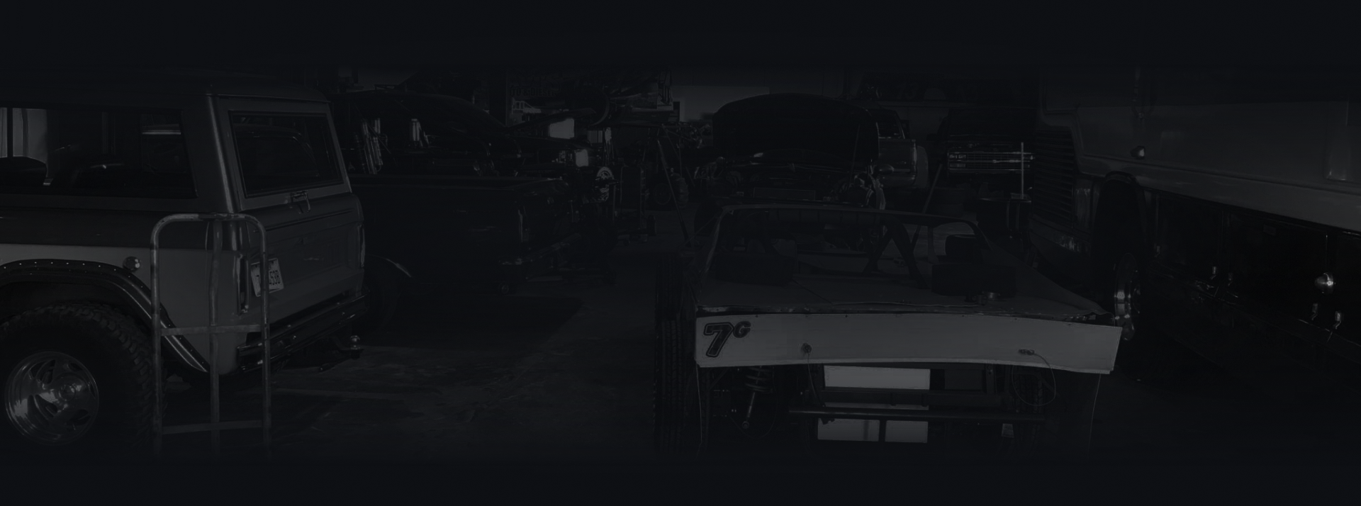 A person working on a car in a dimly lit garage.