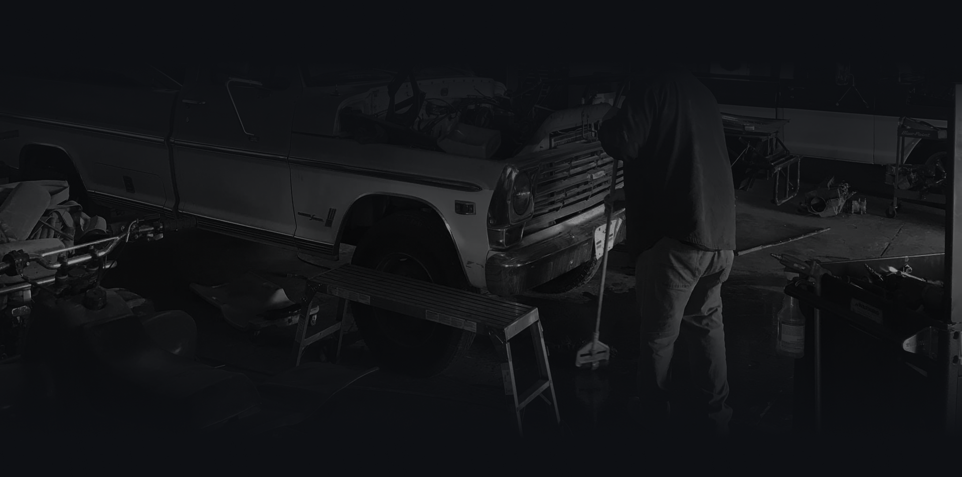 A person working on a car in a dimly lit garage.